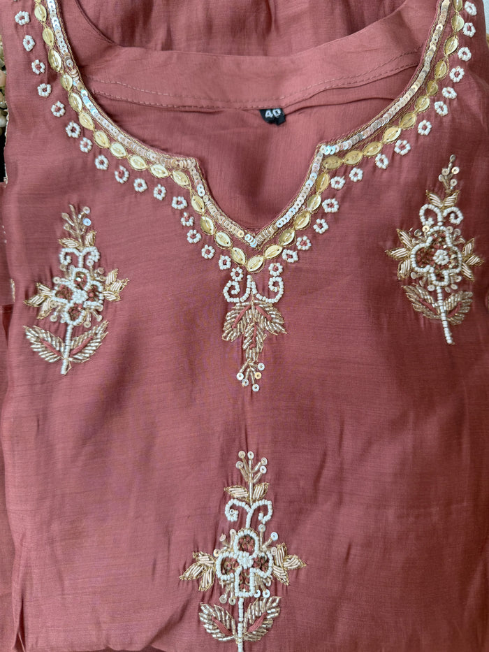 Mauve fabric with gold embroidery on a plain background